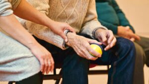 Older gentleman holding a ball with a assistant